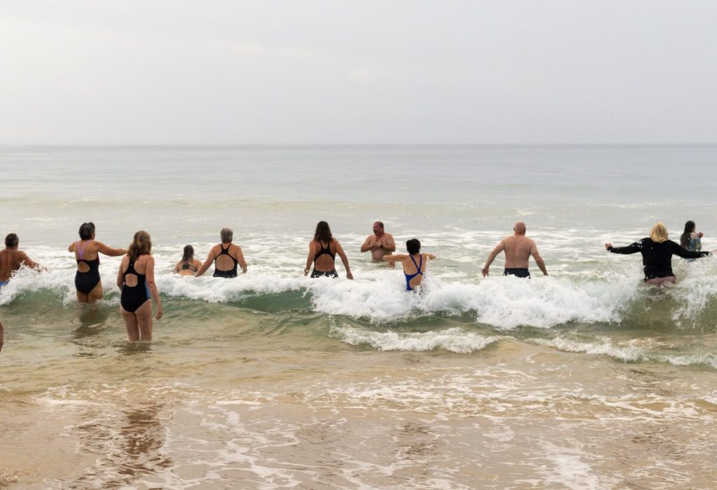 A group of swimmers entering the ocean water.