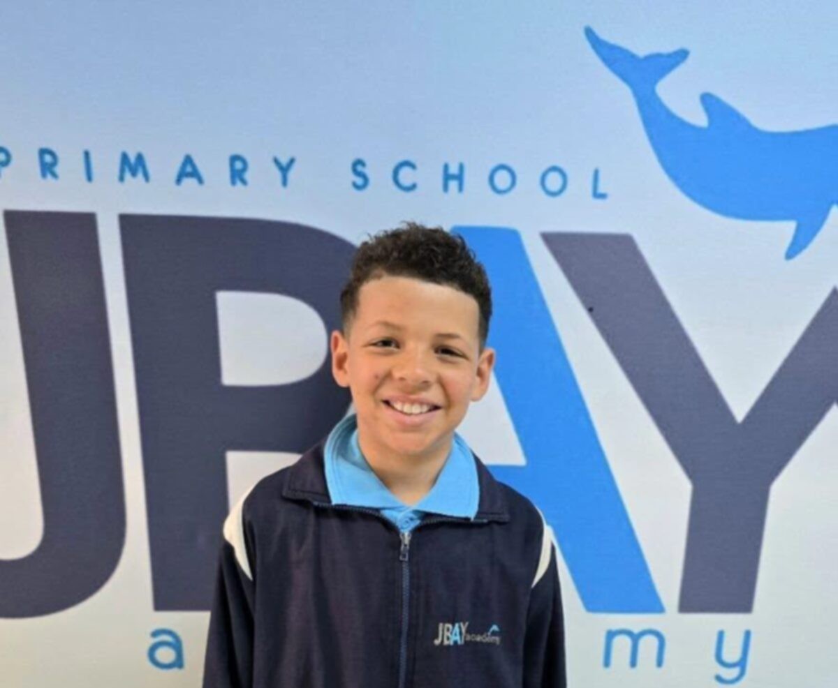 Judah Levendal standing in front of the school's banner.