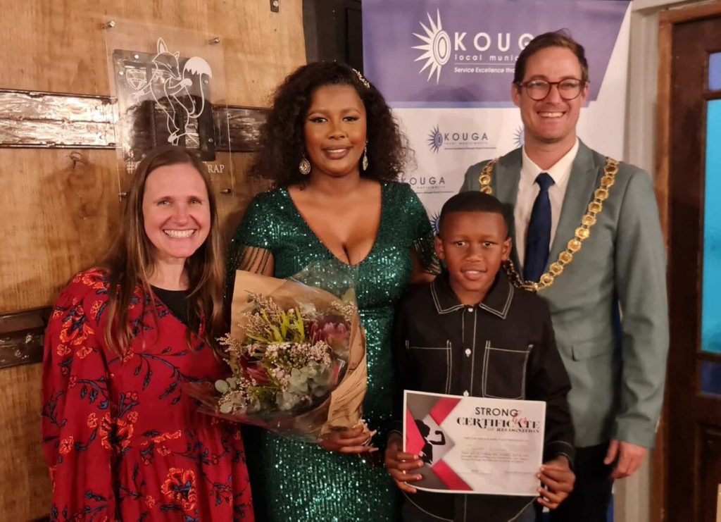 Jenny Waltman (Founder, CEO, and Chairperson of the Board of Grace Klein Community), Ziyanda Kilimani with her son, Iminathi Kilimani (12), and Hattingh Bornman (Kouga Executive Mayor) standing alongside each other.