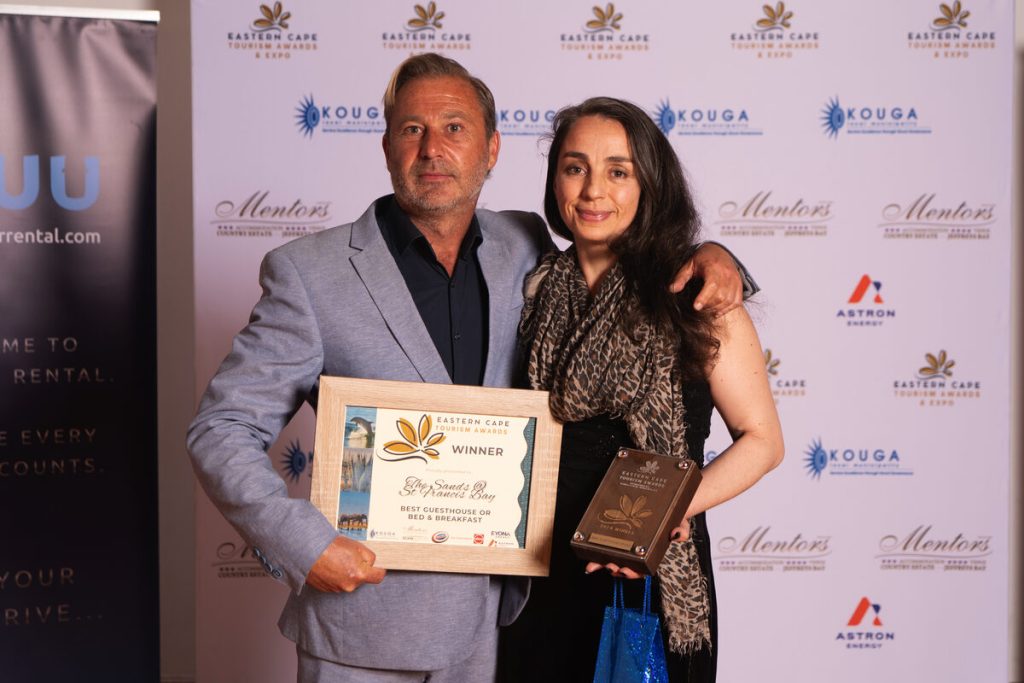 Two people standing alongside each other showcasing their awards.