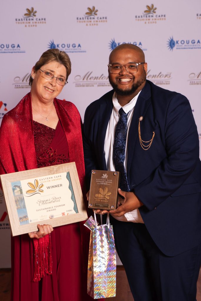 Two people standing alongside each other showcasing their awards.