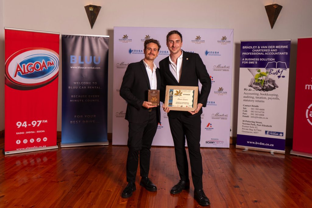 Two people standing alongside each other showcasing their awards.
