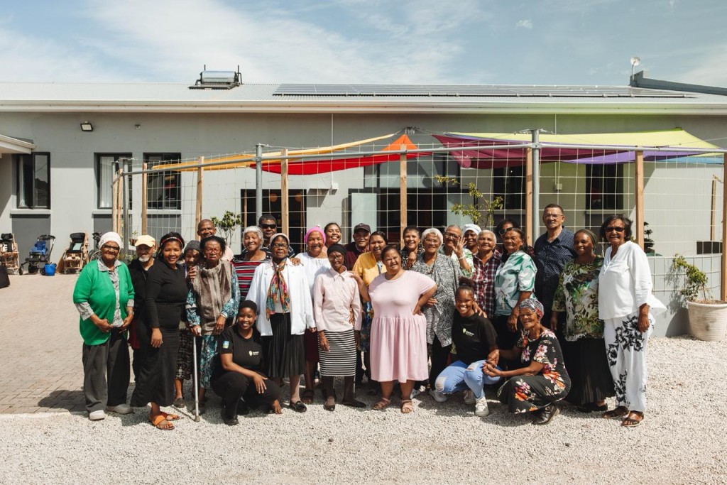 A large group of people standing alongside each other in front of the Rainbow Skills Centre.