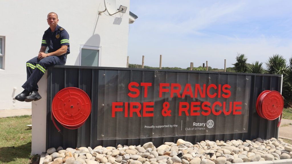 Kouga firefighter Benito Wabanie sitting on the signage at the St Francis Fire Station.
