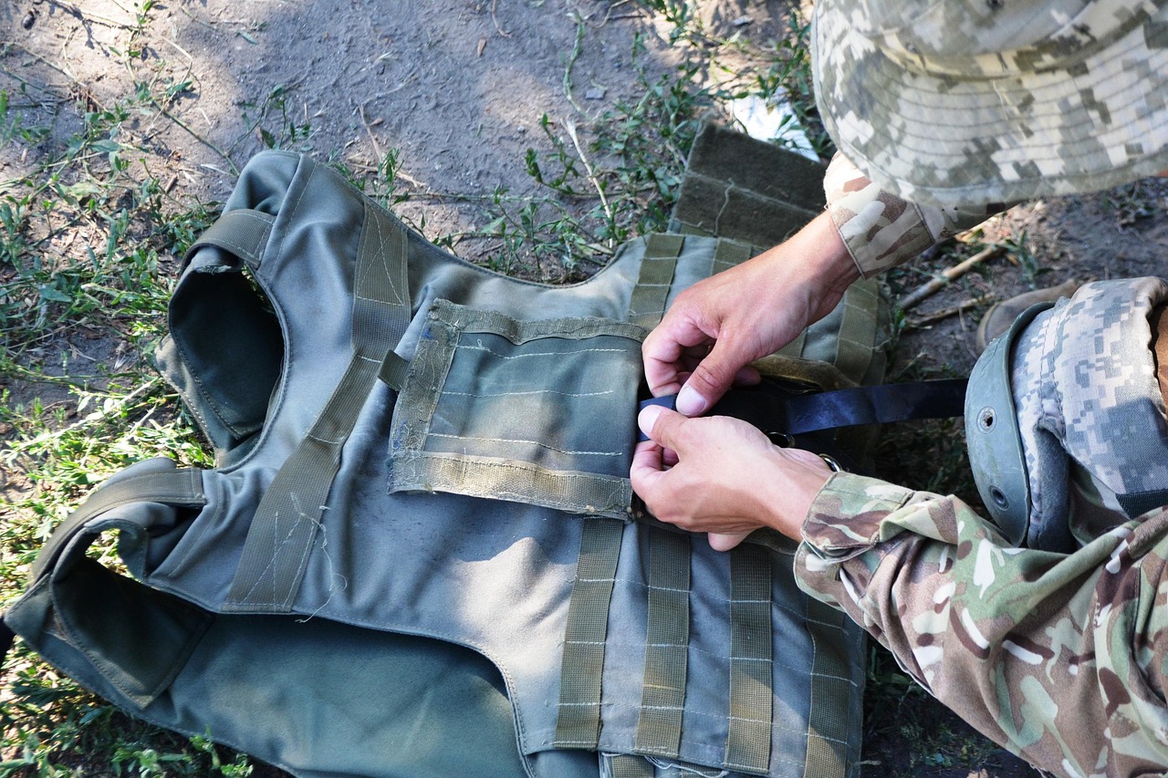 The hands of a soldier buttoning up a bulletproof vest.