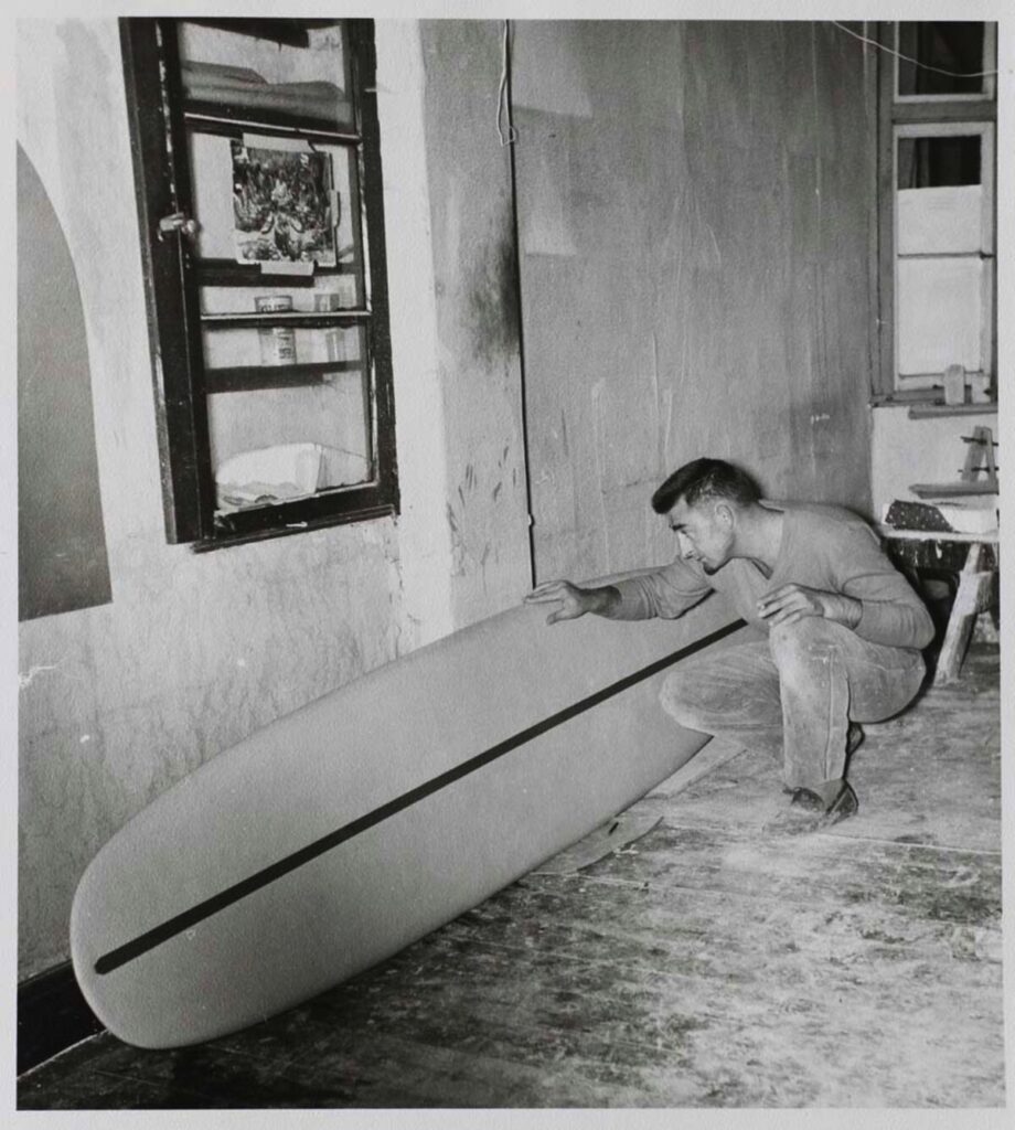 John Whitmore looking at a surfboard.