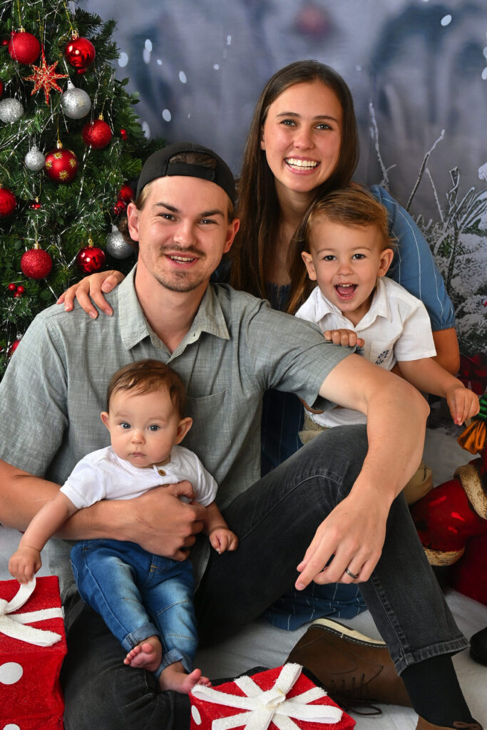 Amand and Nicaile Oosthuizen with their sons, Eliah and Noah sitting alongside a Christmas tree.