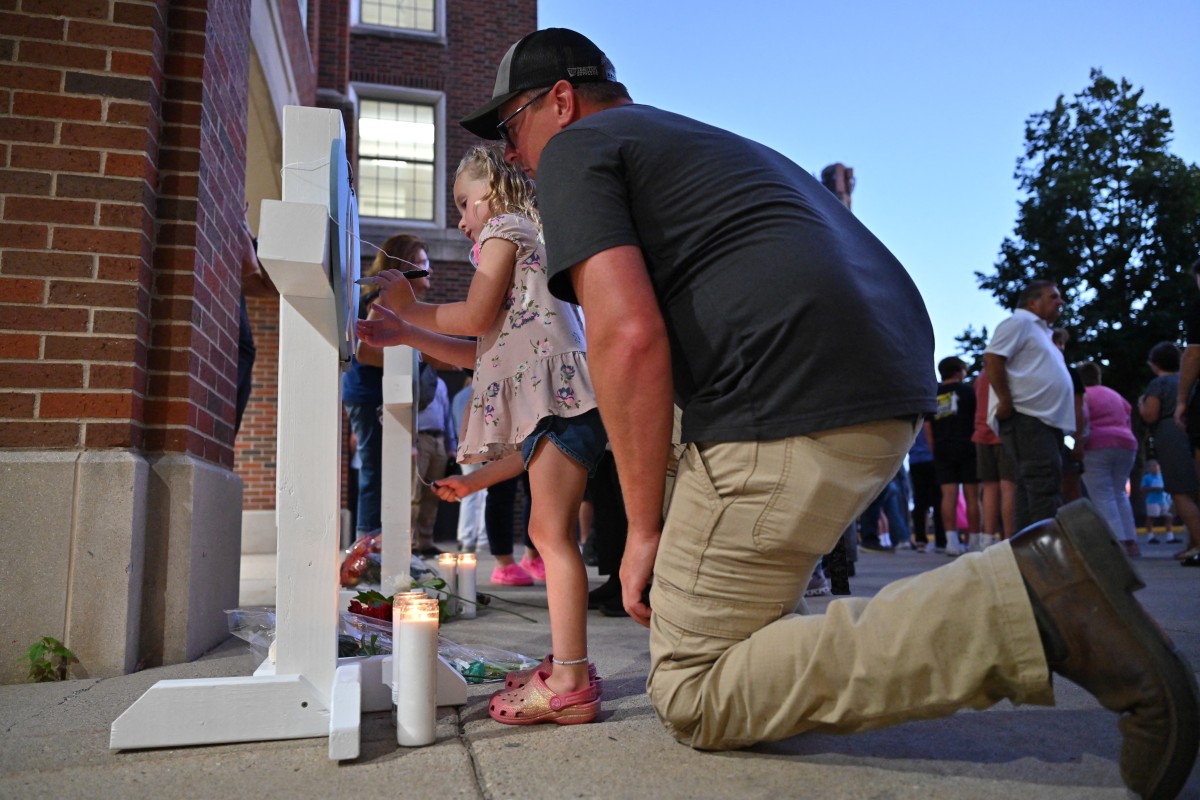 Mourners sign memorial crosses at a vigil at Academy of Holy Angels in Richfield, Minnesota, for the victims of a mass shooting at Annunciation Catholic Church and School in Minneapolis, where two people were killed and 17 injured by a shooter on August 27, 2025. A heavily-armed shooter opened fire on August 27 on school children attending a church service in Minneapolis, killing two pupils and wounding 17 people in the latest violent tragedy to jolt the United States. The shooter fired a rifle, shotgun and pistol before dying by suicide in the parking lot. (Photo by Tom BAKER / AFP)