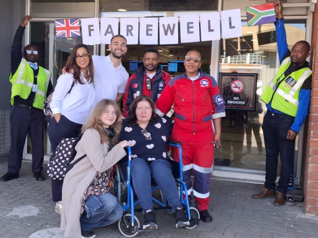 Ebrencia Fourie en haar dogter, met ander persone, by die lughawe. 