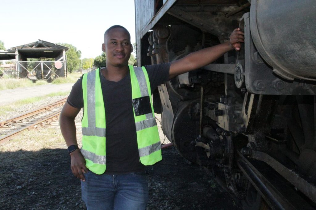 Bakang Seinolo in front of a steam engine.