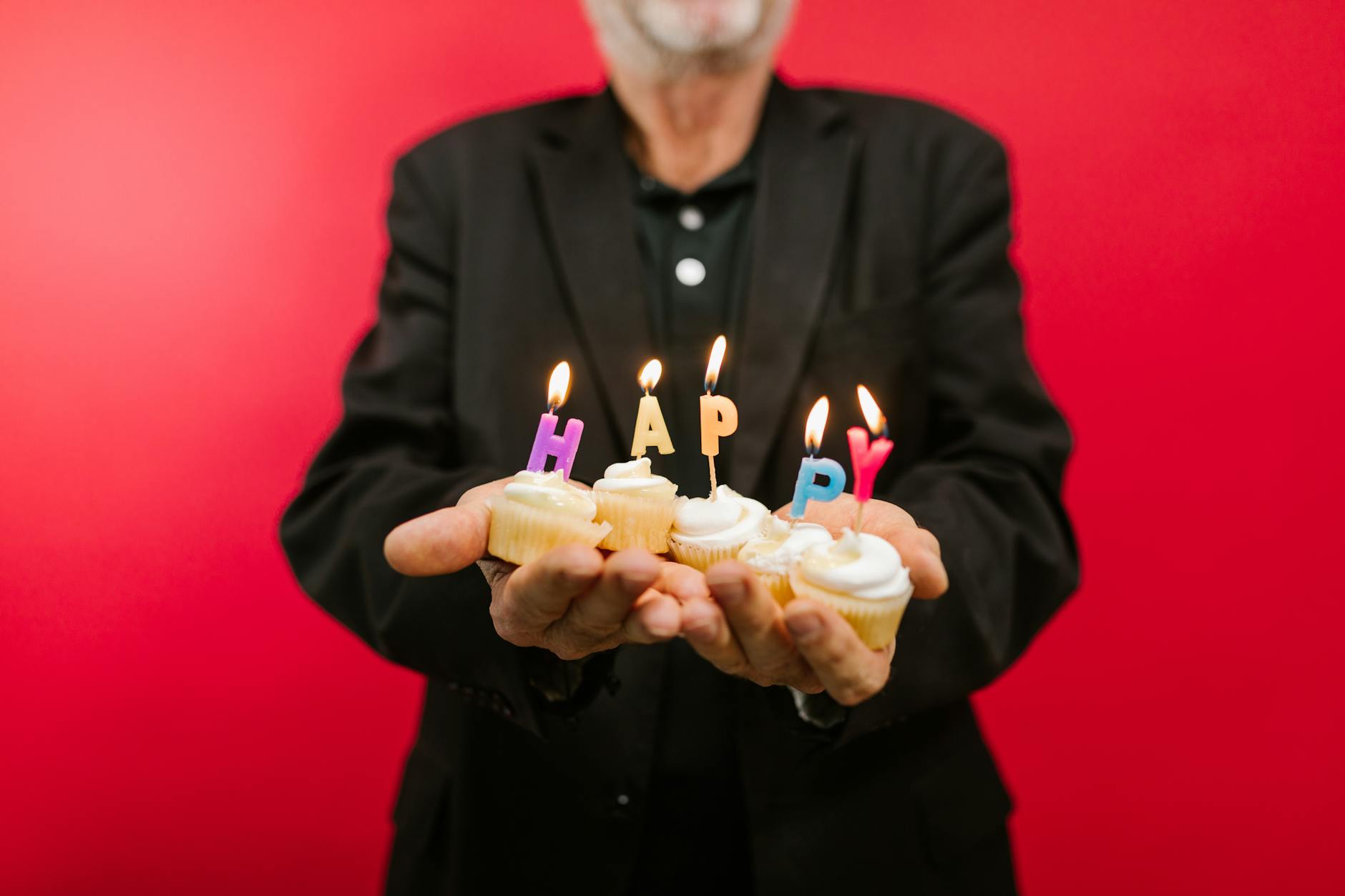 a man in black suit holding cupcakes