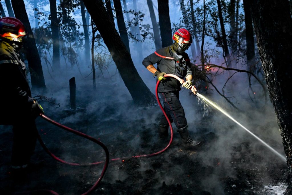 Firefighters work to extinguish a fire as smoke billows in the Broceliande forest.