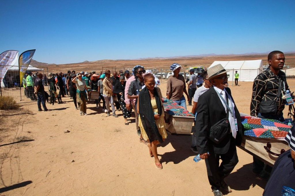 pallbearers carry the coffins to be reburied.