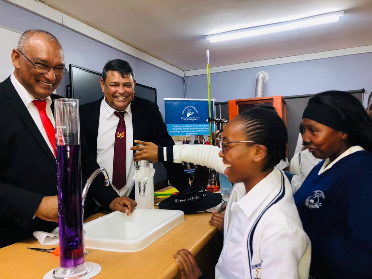 Prof. Shaheed Hartley and John Matthews look on as a Desmond Mpilo Tutu High School learner uses single-ply toilet paper to stop water from spilling out of an upside-down bottle during a science demonstration. Foto: Megan Adendorff