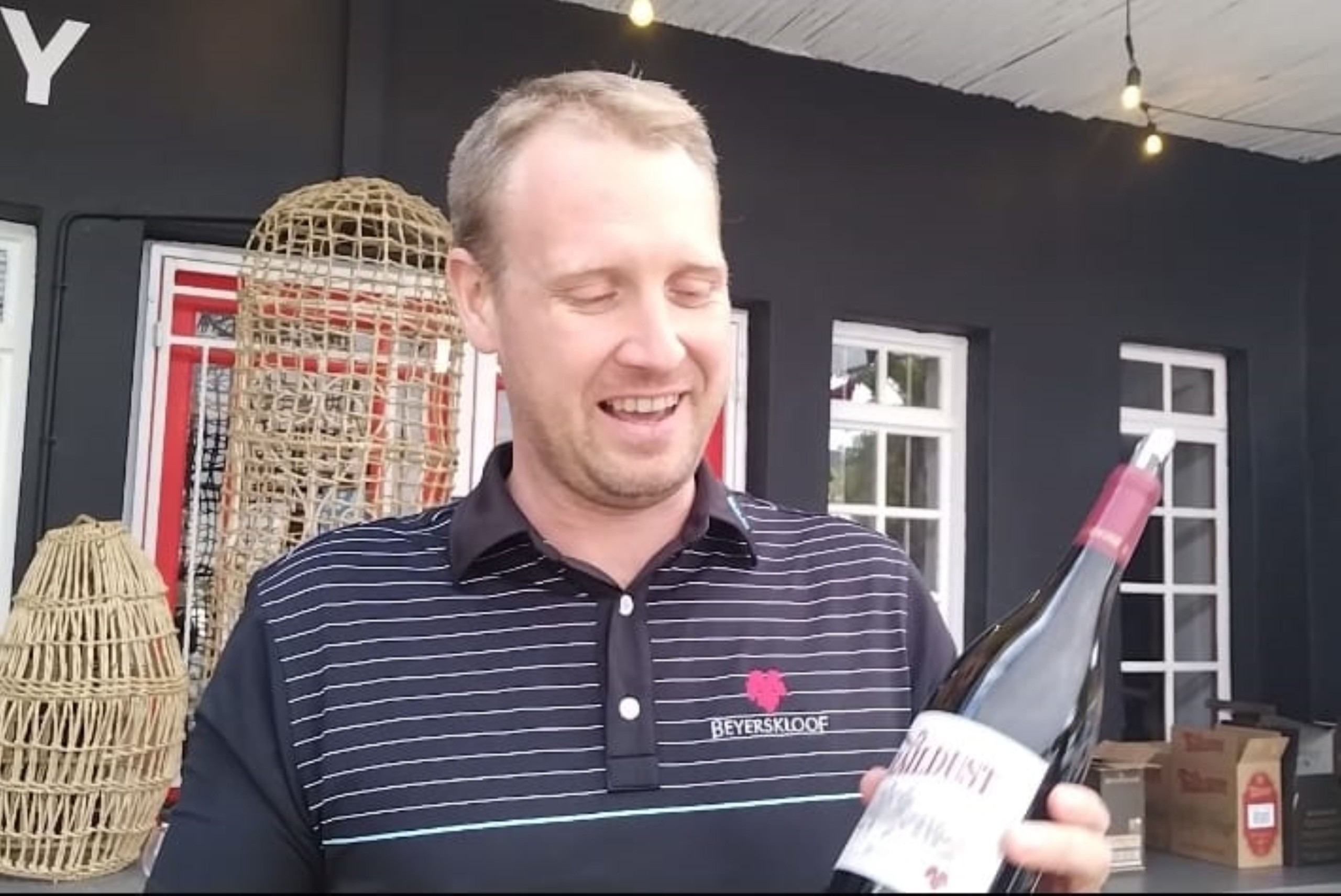 A man standing with a bottle of wine.