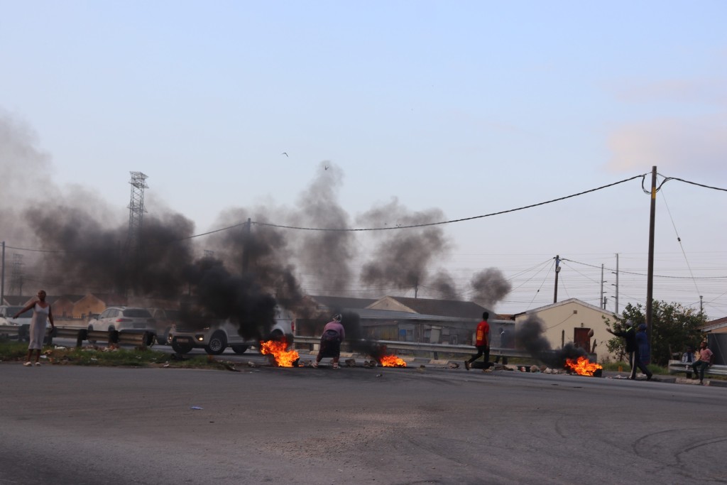 Main protestor in pink chanting, "No food for five days," as she closes road with tyres and debris on 18 August.