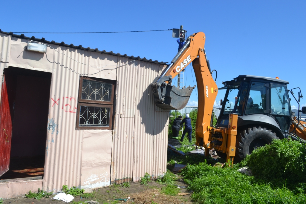 A bulldozer tears through an informal structure during demolitions in Airport Valley.