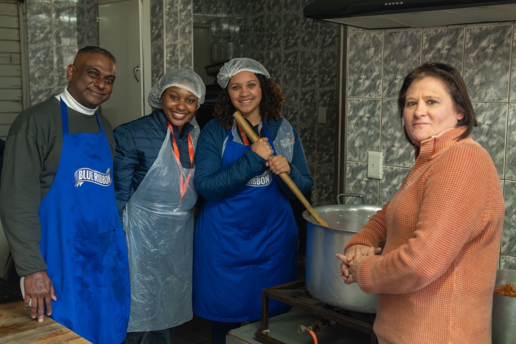 Four volunteers, including members of the Octotel team, preparing a large meal in a kitchen as part of a charity event.
