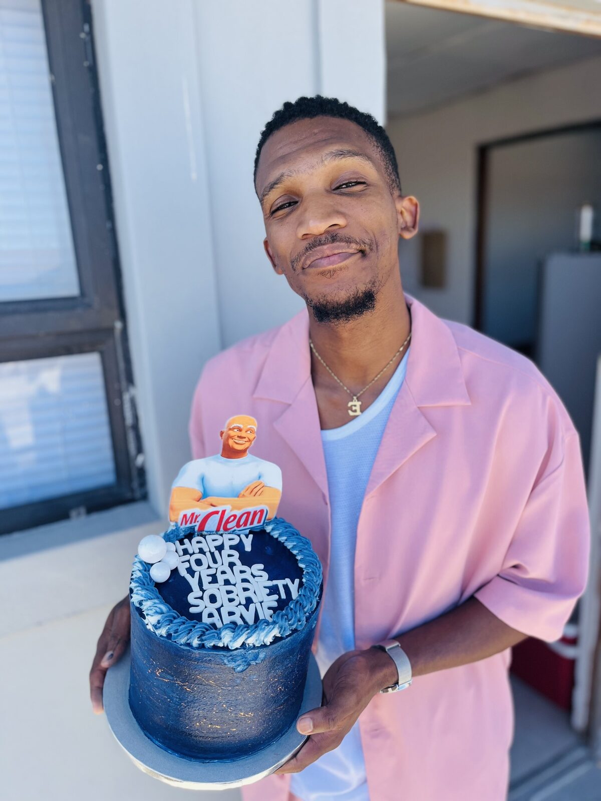 Avuyile Mackenzie celebrates five years of sobriety by holding up a cake when he celeberated year4 , marking his milestone with friends and family.