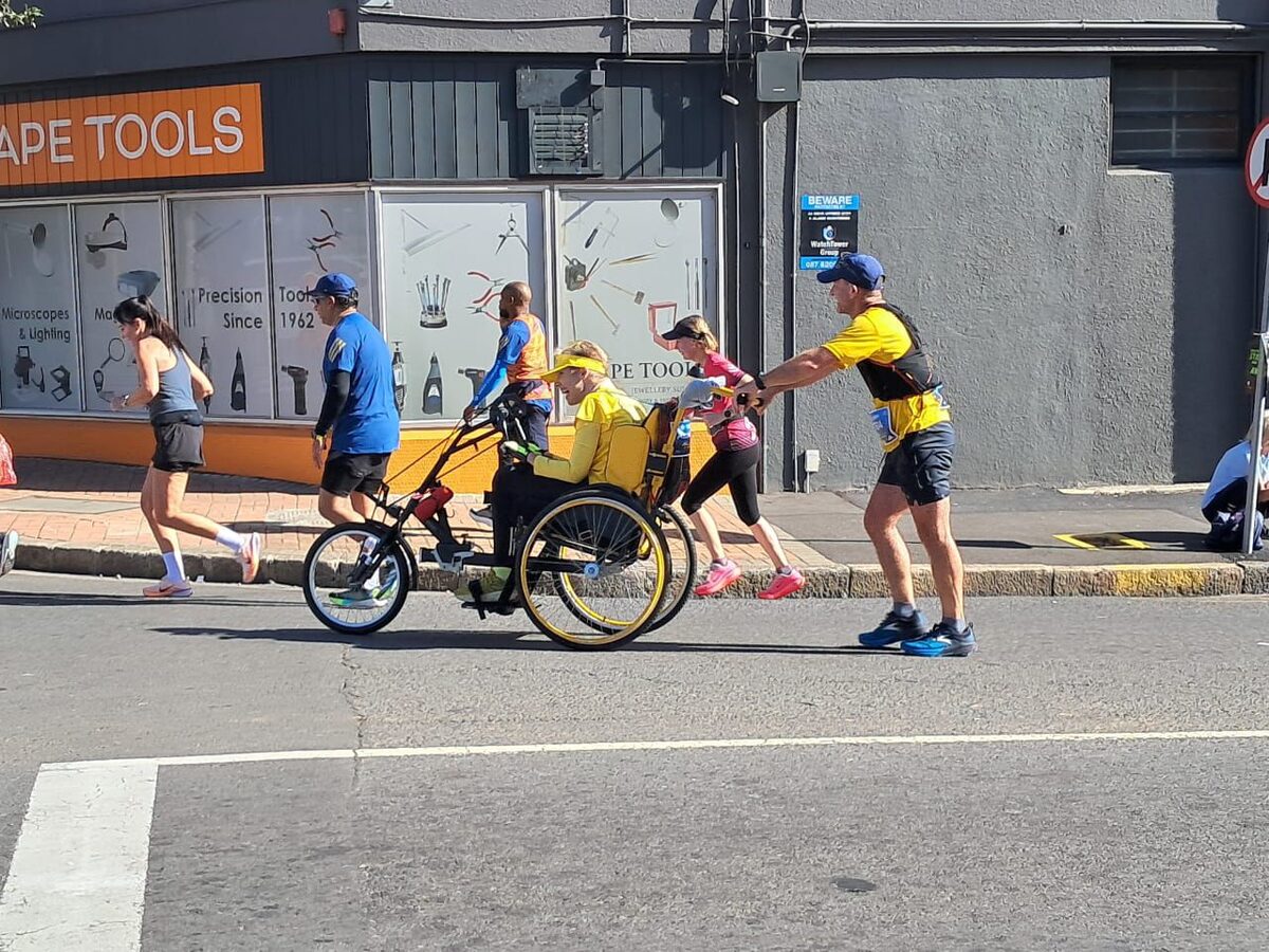Zimele Cape Town Marathon team in yellow T-shirts crossing the finish line on 24 May 2026