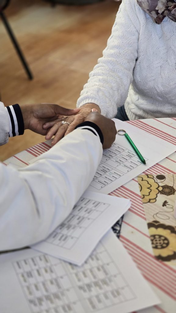 A Wittebome High School learner massages the hand of a resident during the Outreach Programme's visit to a nearby old age home. Photo: Supplied