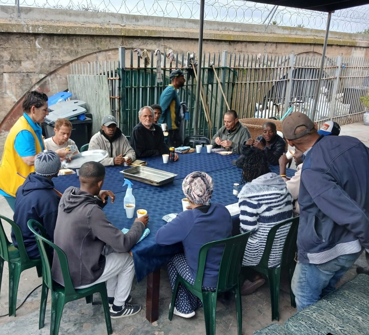 Lions Club of Tokai members and mothers from the Thula Baba Project play with Lego on a table during a Mandela Day