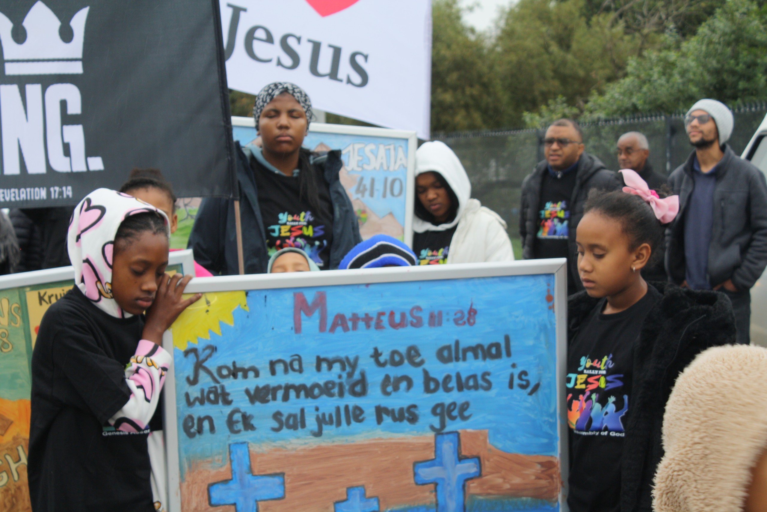 Jeugdiges wat spog met handgemaakte plakkate.