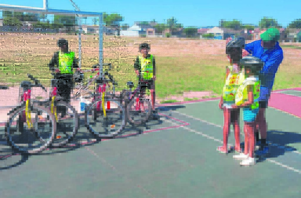 Photo of Winston Middleton helping a youngster with a cycling helmet.