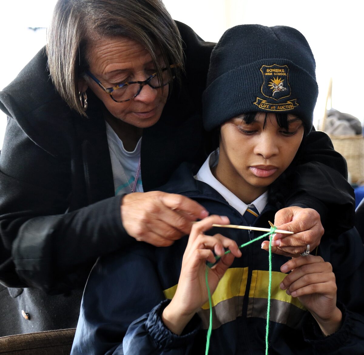 Cheryl Johnson from Coin Care shows Aliyah Johannes how to knit.