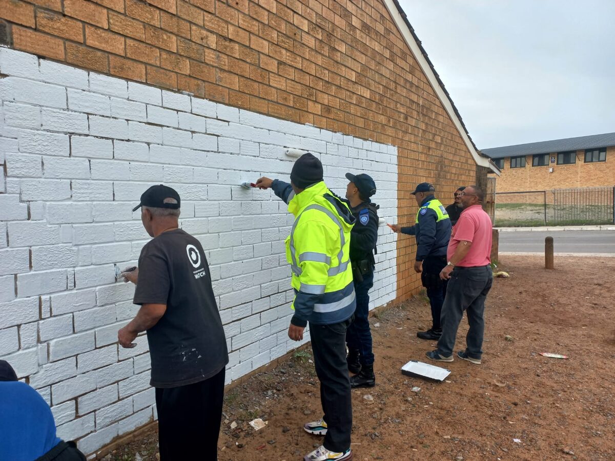 Law enforcement officers stop by briefly to help neighbourhood watch members paint over gang tags in Eastridge.