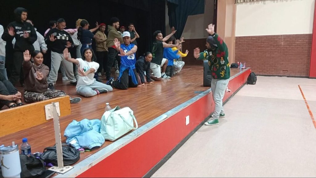 Shamieg George demonstrates a dance move to the Devolution dance group who turn 25 this year.