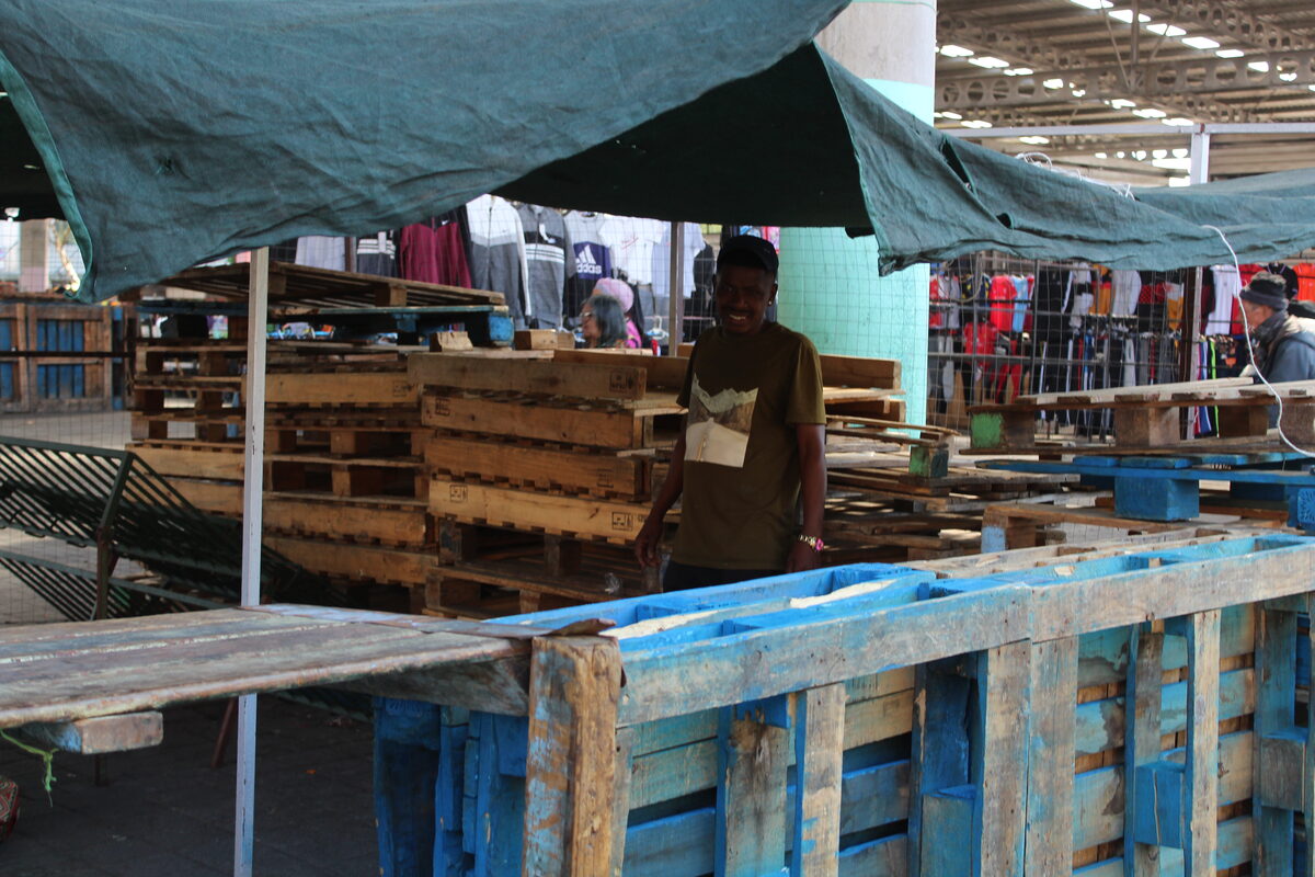 Tash-Riek Erasmus stands against a wall of pallets that are used to secure his stall in the Town Centre overnight.