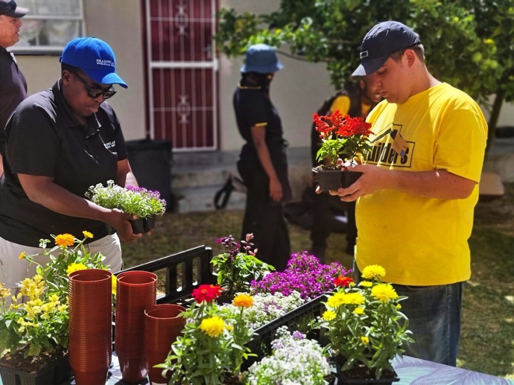 Noluvuyo Mbuthuma van Shadowlands en Reece Faria van Builders sit hand by met die plantjies.