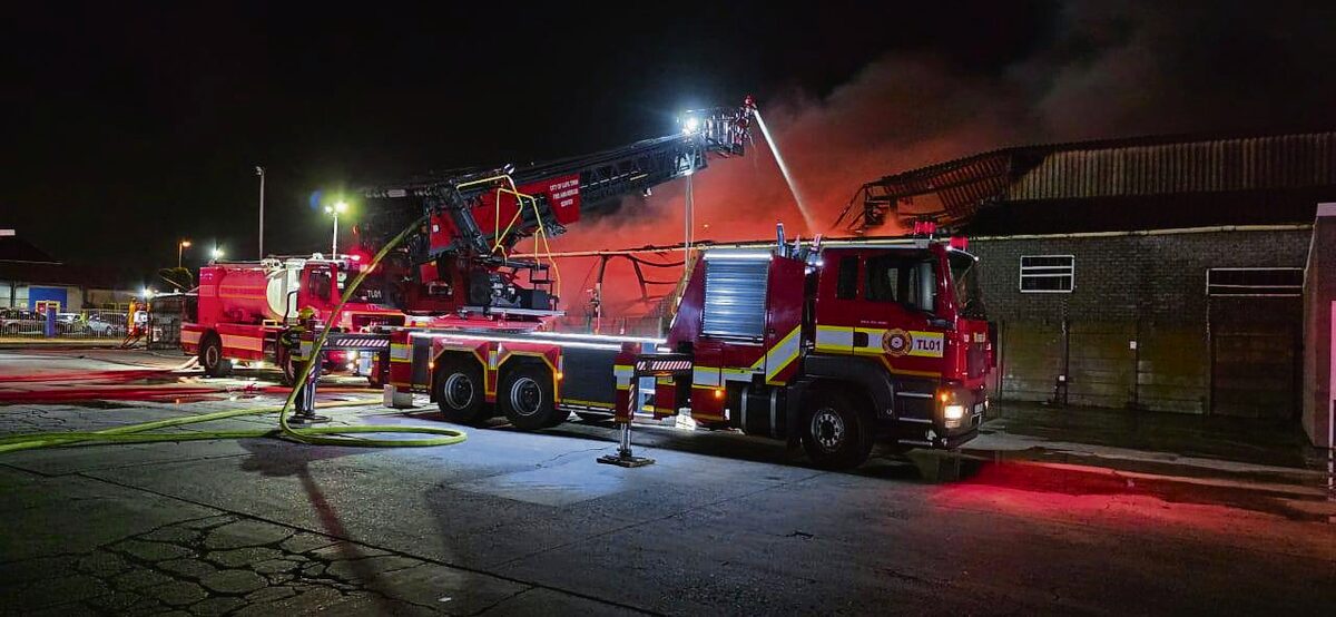 An aerial platform sprays thousands of litres of water into the burning warehouse.