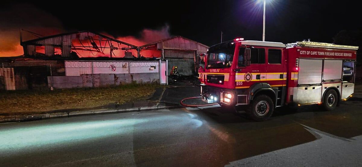 Flames rise high above the walls of the warehouse.