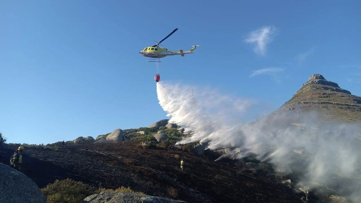A helicopter swoops in with a critical water drop over the Cape Town blaze. Photo: SANParks