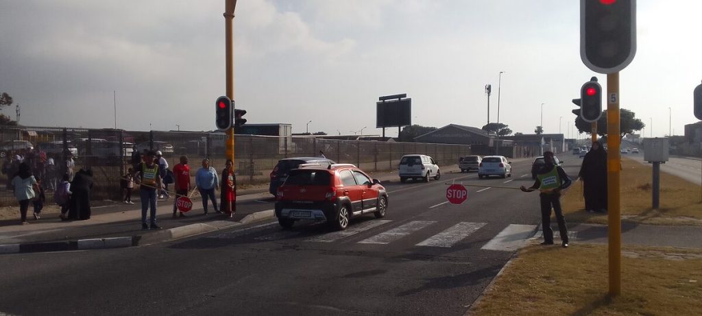 A car jumps the red light at a pedestrian crossing while the scholar patrol boom is lifted. 