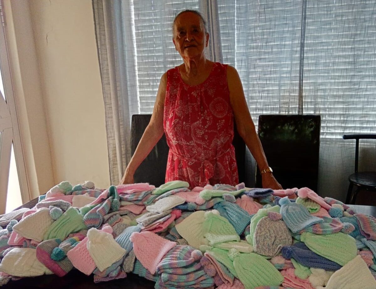 Blanche (Barney) Meyer (91) with the self-knitted beanies in front of her.