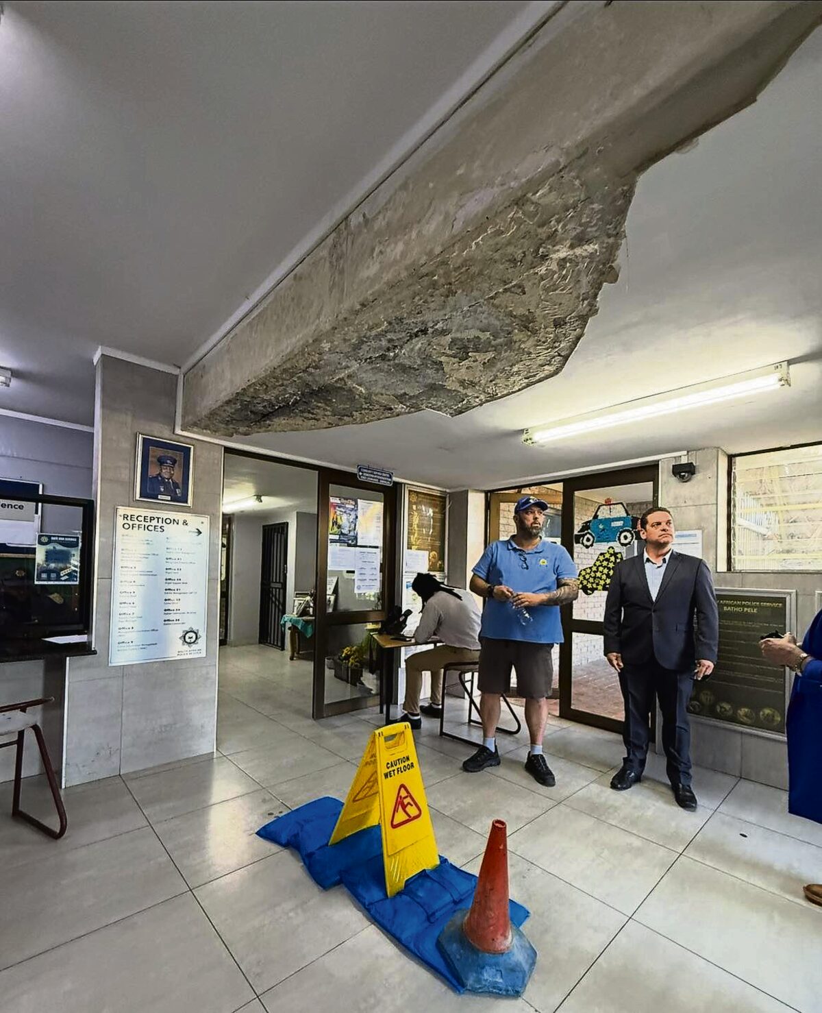 Councillor Jonathan Mills inspects the damaged ceiling at Table View Police Station's charge office, highlighting urgent repairs needed to ensure safety.
