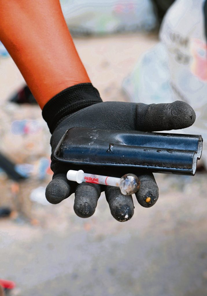 'n Metropolisiebeamte wys die dwelms wat hy gevind het. Dit was in die houer versteek.