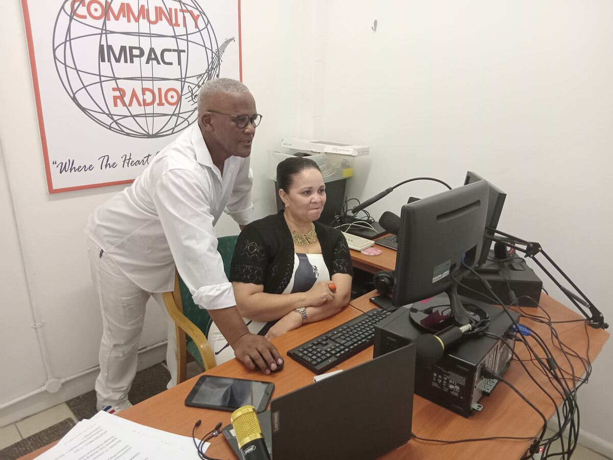 James Tempers and Cecelia Less load the upgraded software from the computer that runs Community Impact Radio.