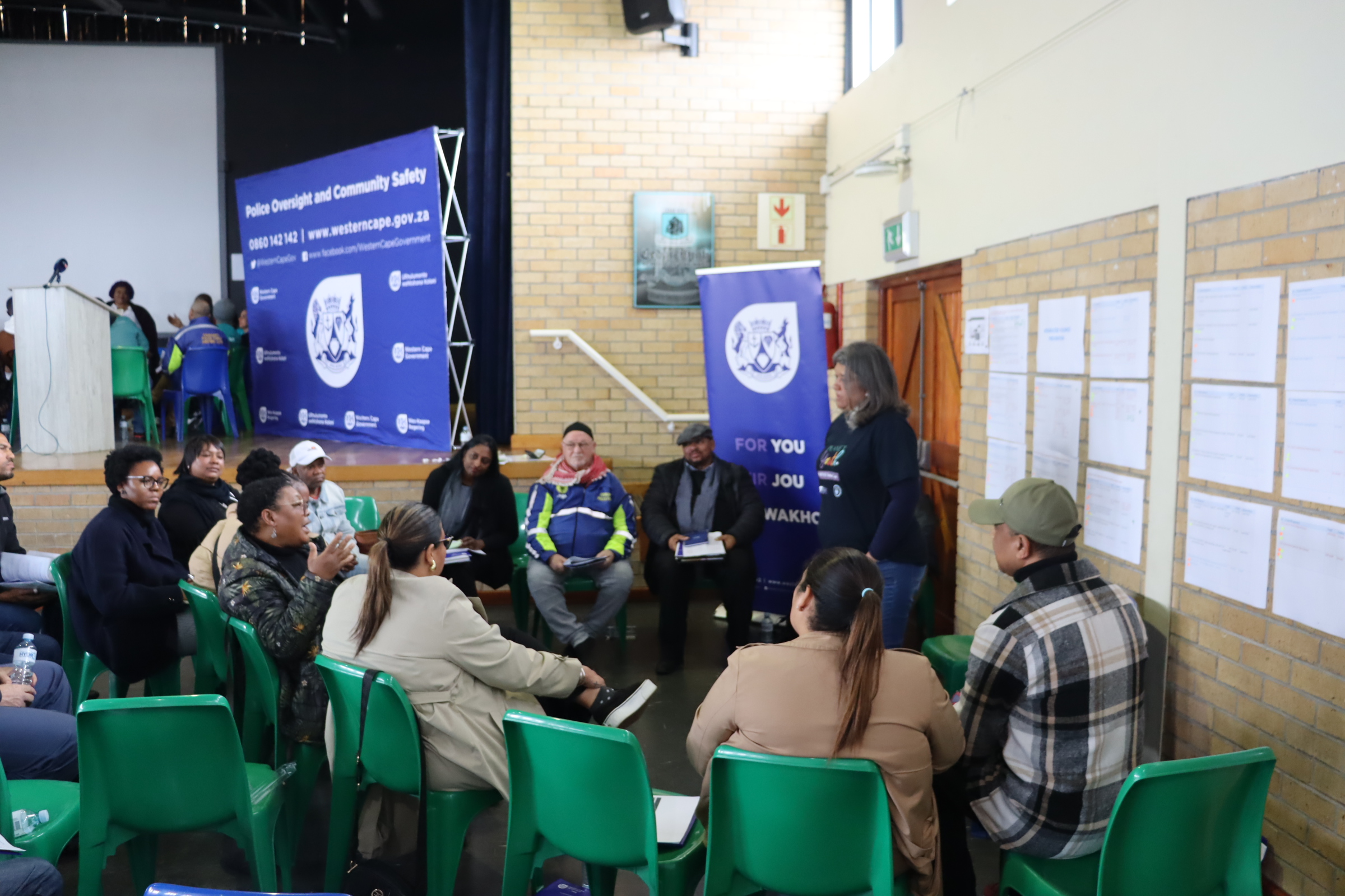 a group sits in a circle in front of a banner