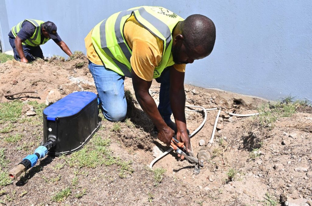 A City employee connects a replacement water meter.