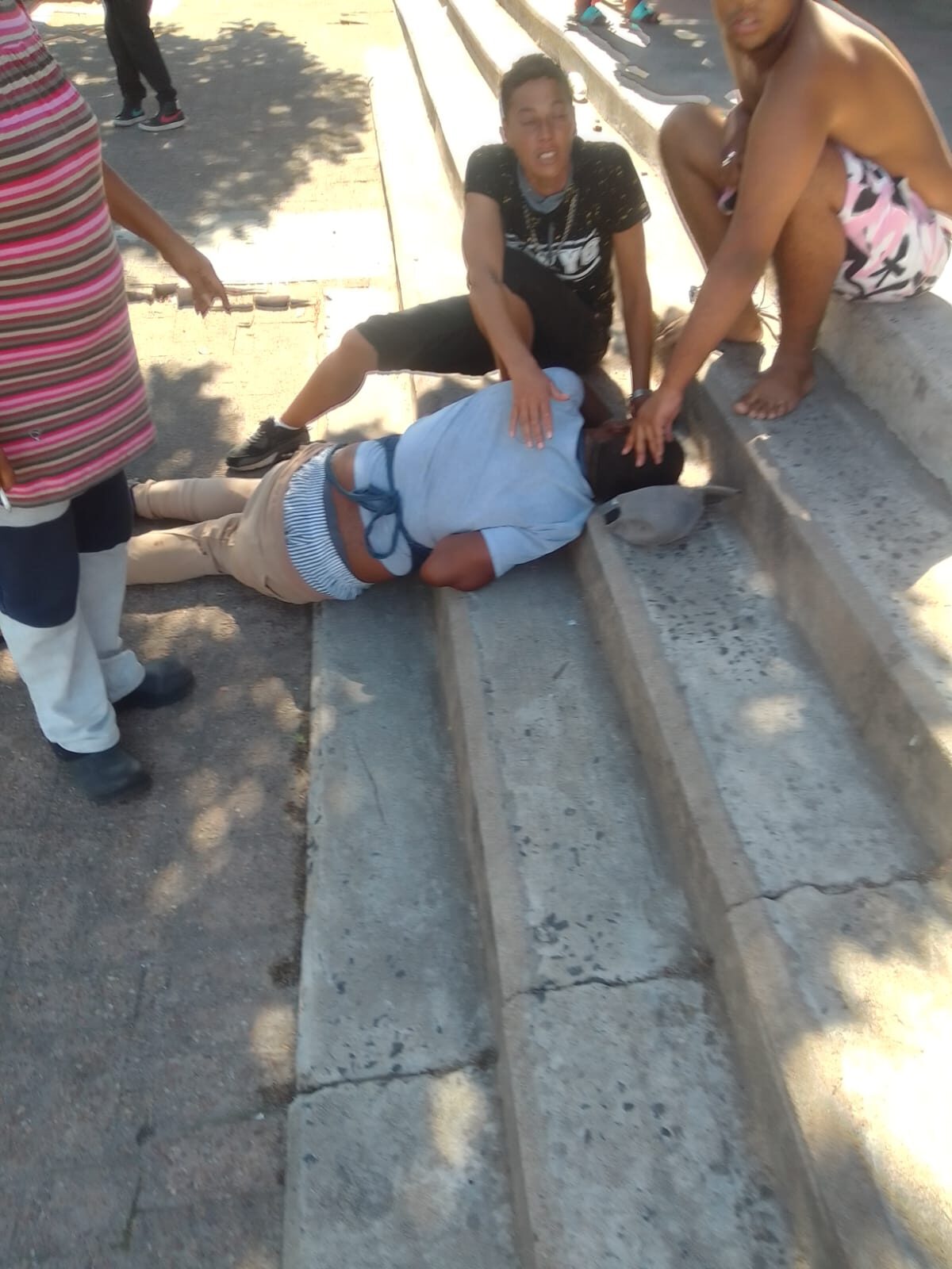 Young boys attend to a third boy who was shot in alleged gang crossfire.