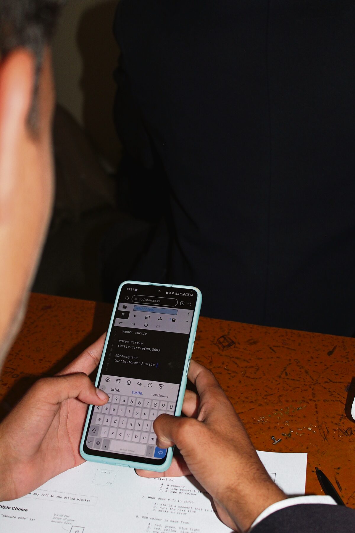 A pupil uses code to draw a set of shapes from an application on his cellphone.