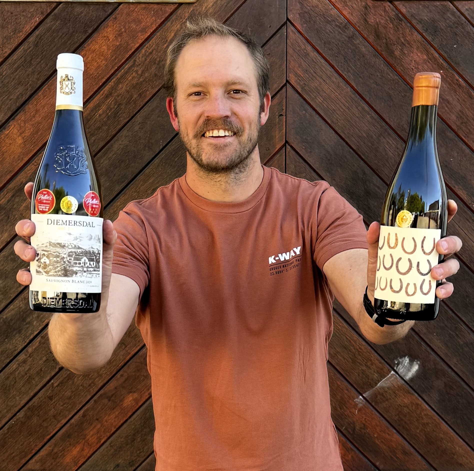 Juandré Bruwer, winemaker, with the two winning wines in front of the Diemersdal wine cellar.