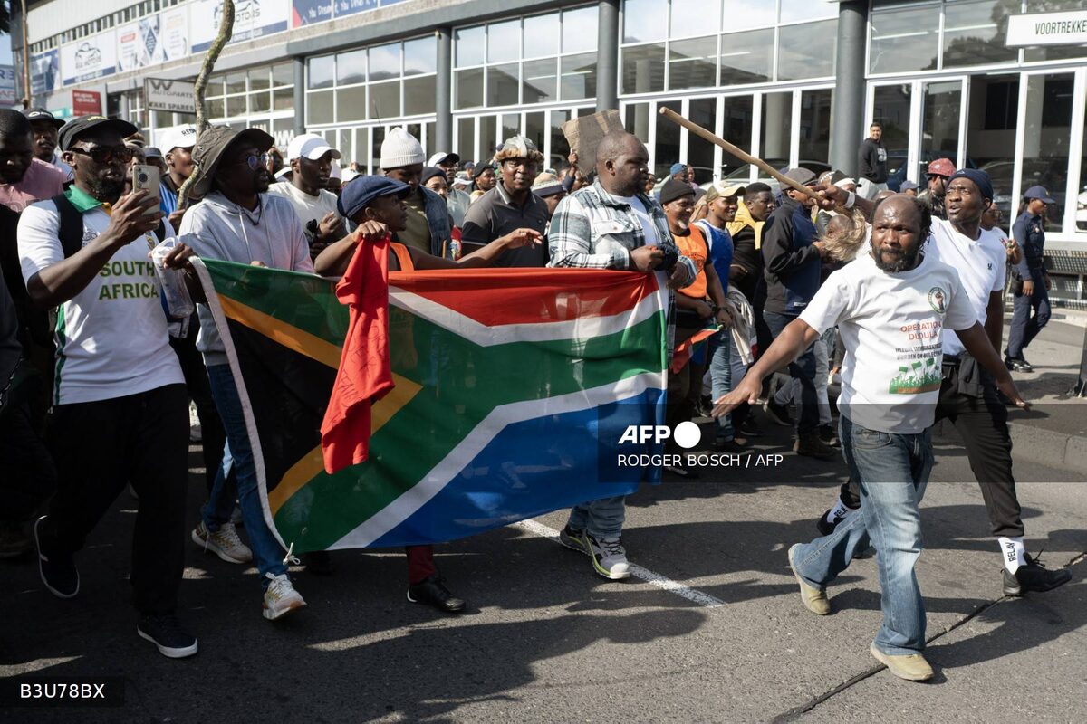 Demonstrators hold a South African flag as they march during a protest against undocumented migrants organised by the March and March and Operation Dudula groups in Cape Town on May 23, 2026. (Photo: AFP)
