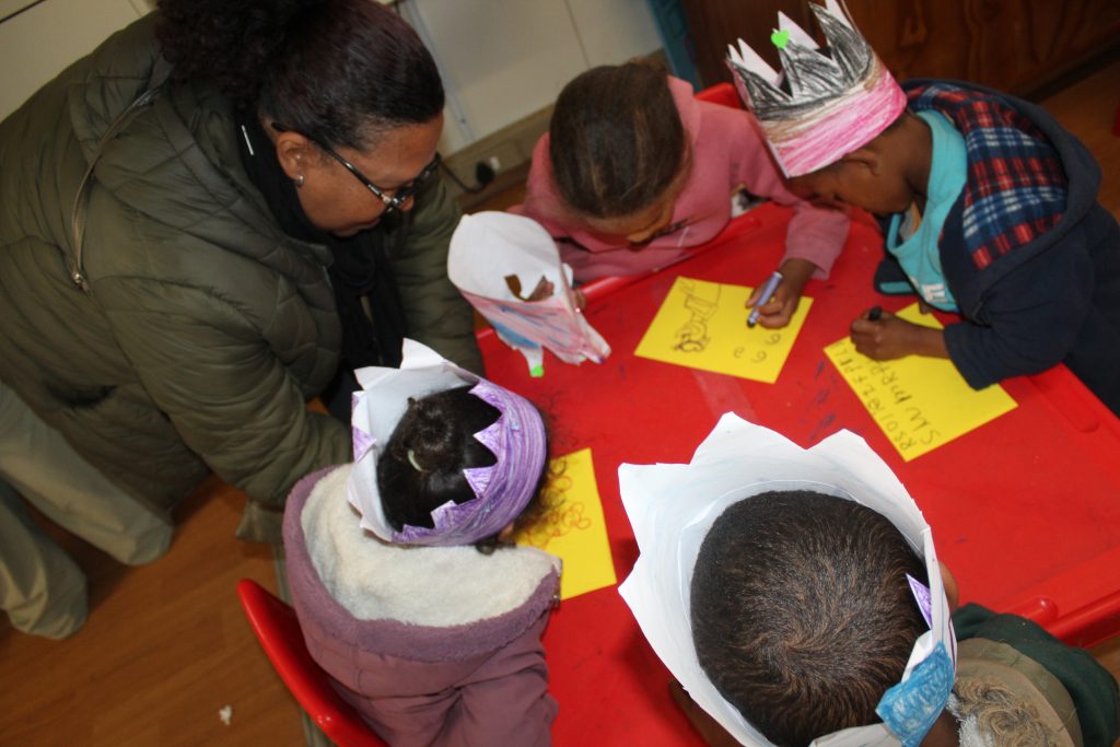 Advance Edukos's Wendy Abrahams helps children to draw at a trauma-informed holiday programme.