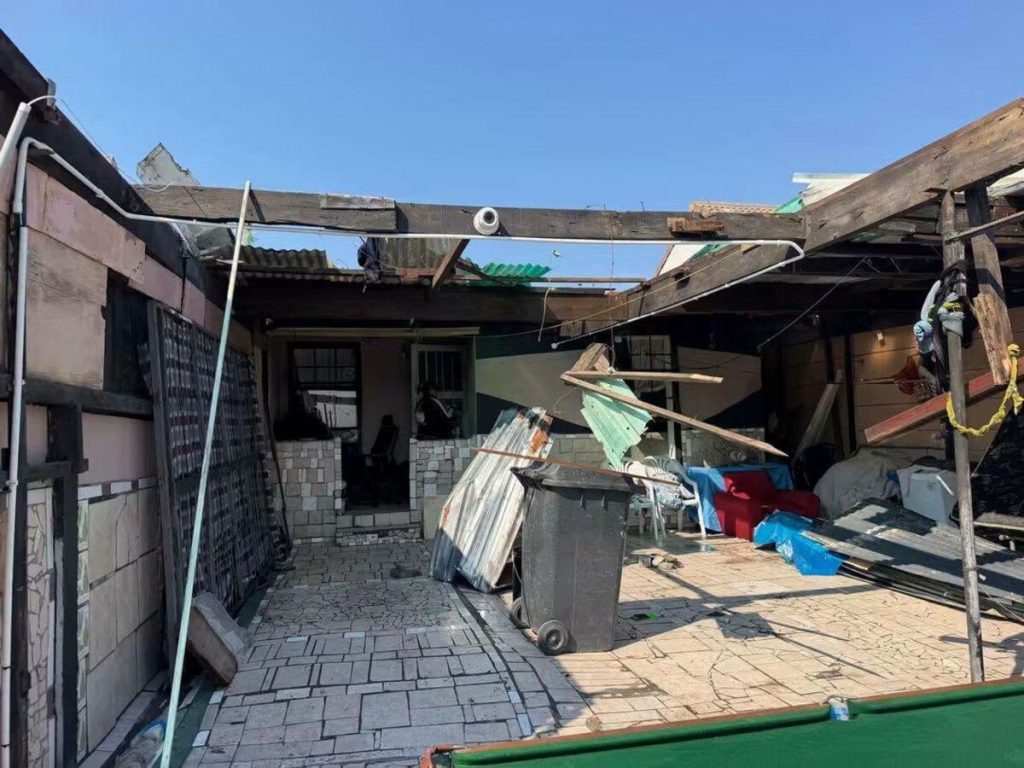 A formerly enclosed backyard is left exposed after strong winds.