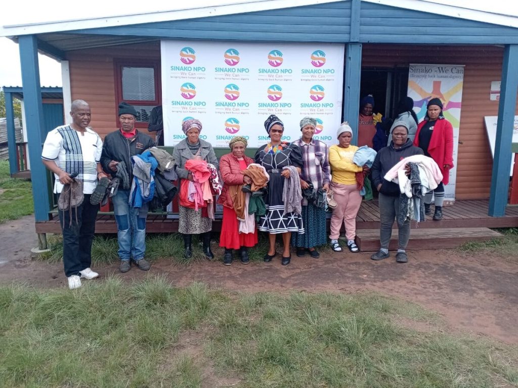 On the left is Sinako NPO founder Mzukisi Toba delivering clothes and blankets to community members.